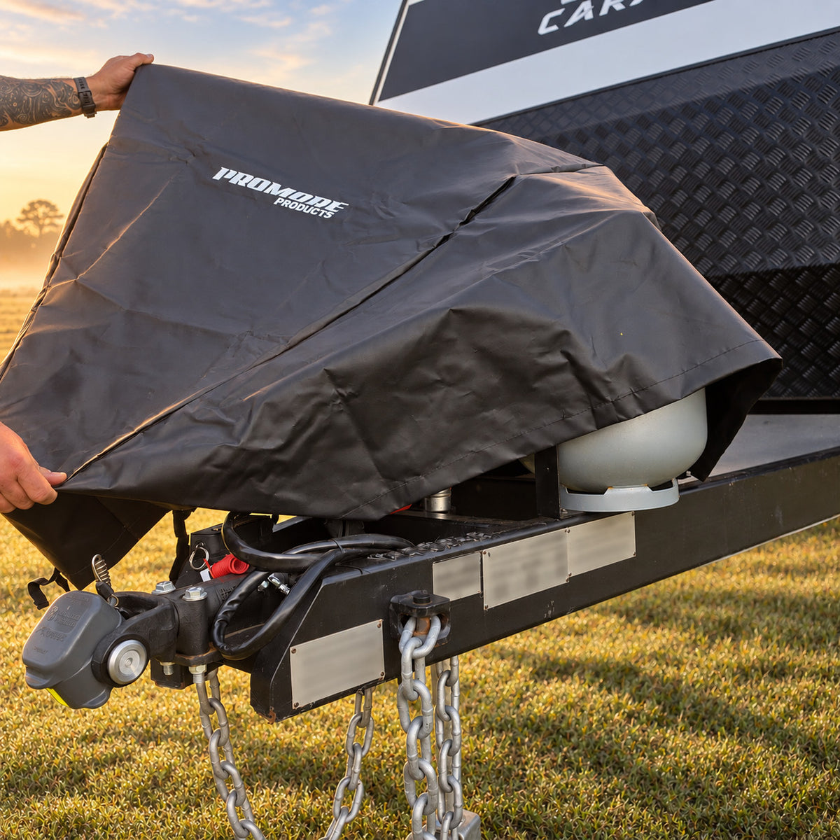 Pulling the hitch cover back over a gas bottle on the drawbar in golden morning light