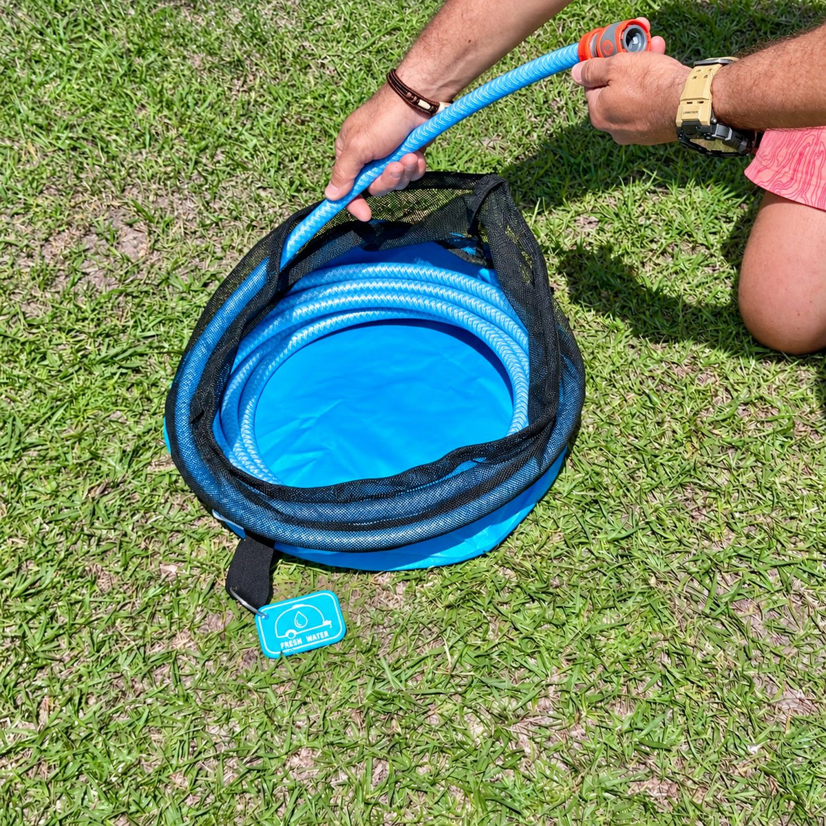 Drinking water hose being coiled into the blue hose bag on the grass
