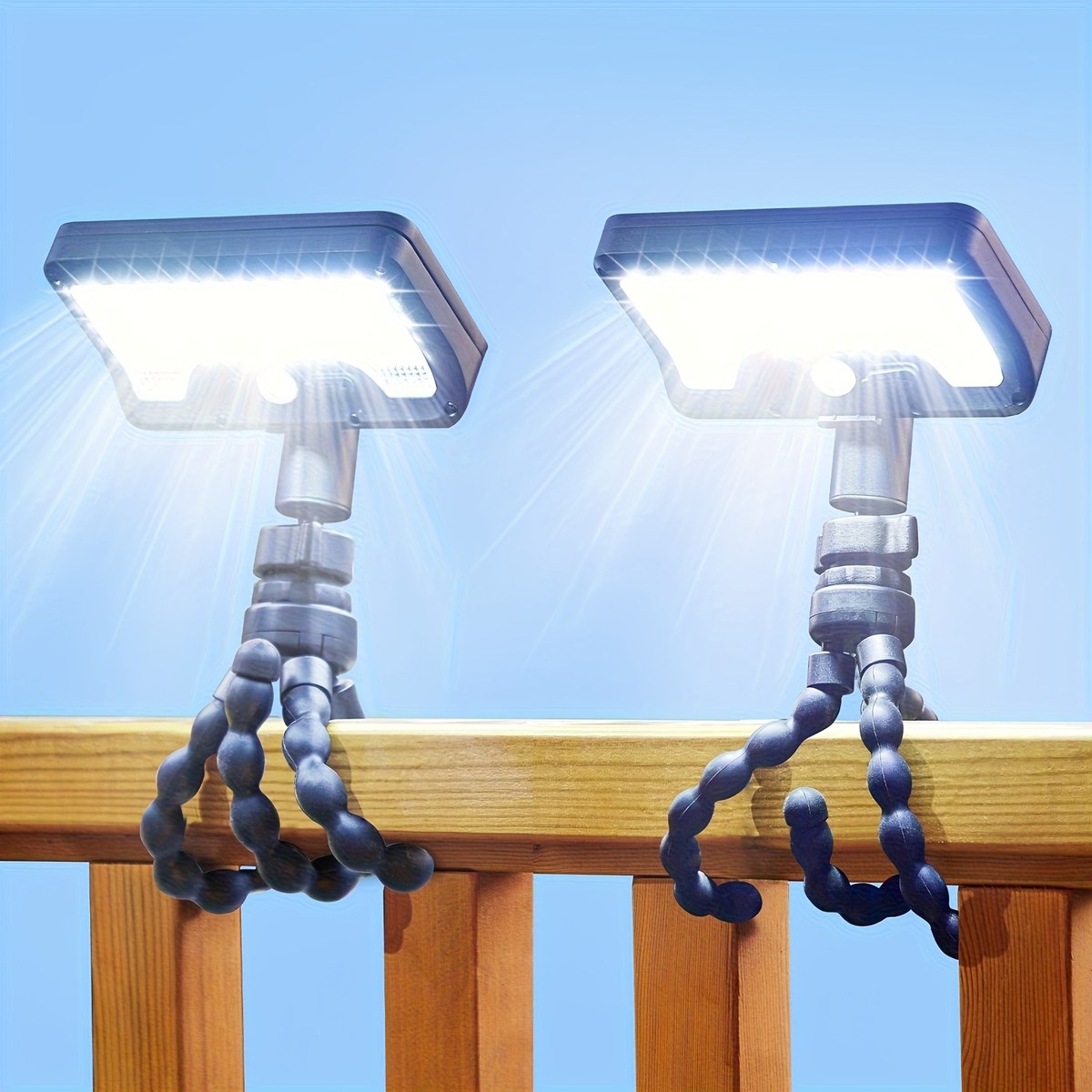 Pack of 2 solar motion sensor camping lights with flexible tripod legs wrapped around a timber deck rail