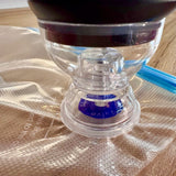 Close up of the clear sealer nozzle sitting flat over the blue air valve on a vacuum bag