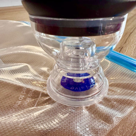 Close up of the clear sealer nozzle sitting flat over the blue air valve on a vacuum bag