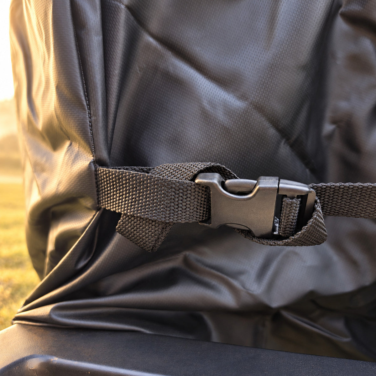 Close up of a webbing strap and buckle holding the cover snug in warm morning light