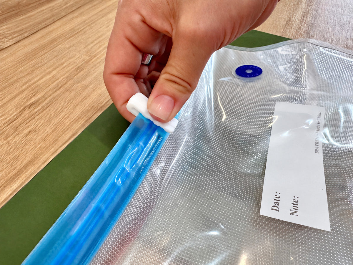 Sliding a sealing clip along the zip of a Promore vacuum bag to close it