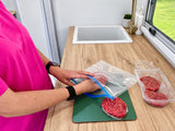 Loading burger patties into a resealable Promore vacuum bag on a caravan bench