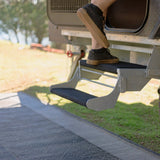 Foot stepping onto a galvanised double caravan step fitted with black marine carpet step rugs