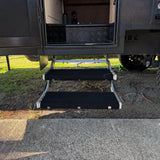 Aluminium double caravan step with rugs fitted, seen front on below an open caravan door
