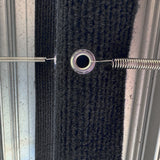 Close up of a tension spring hooked through a metal eyelet on a marine carpet step rug
