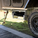 Galvanised double step folded away under a camper trailer with the step rugs still fitted