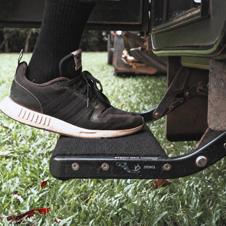 Shoe stepping onto a single pull out caravan step fitted with a marine carpet rug