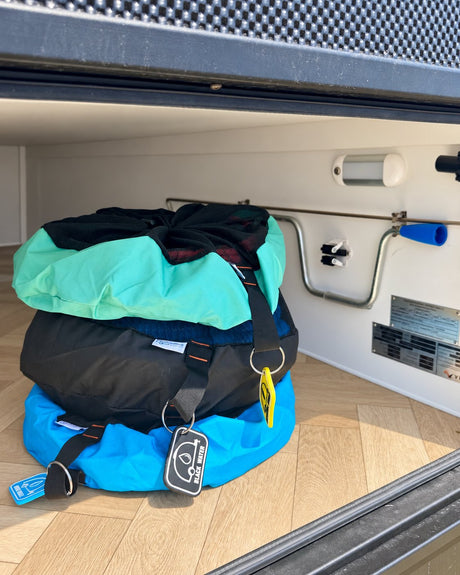 Green, black and blue caravan storage bags stacked inside a caravan storage hatch