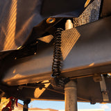 Cable lock threaded through a webbing loop under the cover and around the drawbar in warm evening light