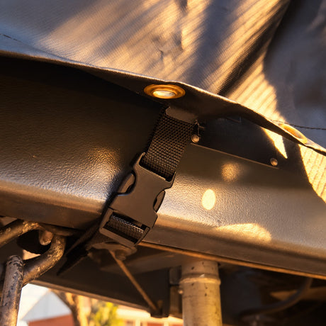 Webbing strap and buckle under the cover clipped across the drawbar in warm evening light