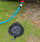 Black sullage hose bag on the grass beside the caravan waste outlet with the sullage hose connected