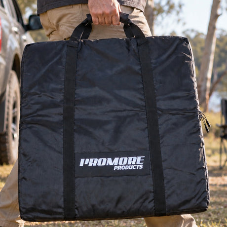 Person carrying the Promore Products Trestle Table Bag by its handles at a bush campsite